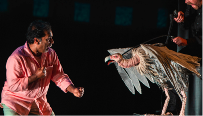 Gerry the vulture puppet and actor Jacob Rajan in a pink shirt looking scared