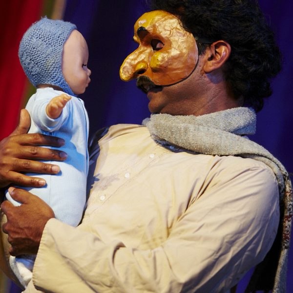 Gobi (Jacob Rajan wearing a half mask) and Baby Apu (a doll in a blue bonnet).