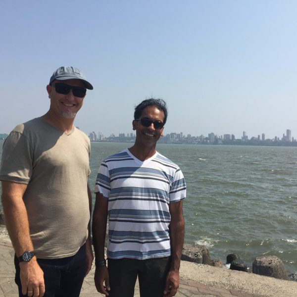 Jacob Rajan and Justin Lewis stand in front of the water on a boardwalk