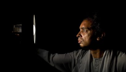 Actor Jacob Rajan stands looking into a lamp