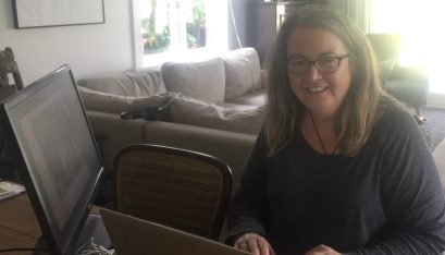 Jane sits at her desk with her computers in her living room