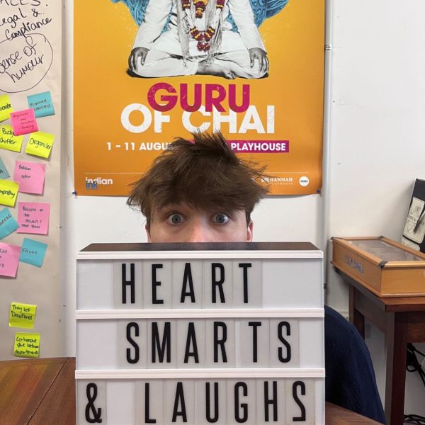 Image of a young male with his head popping out from behind a sign that says Heart, Smarts and Laughs