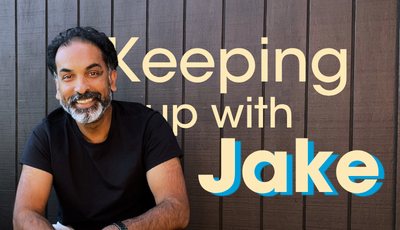 Smiling bearded man in black shirt beside bold text "Keeping up with Jake" on a dark wood-panel background.