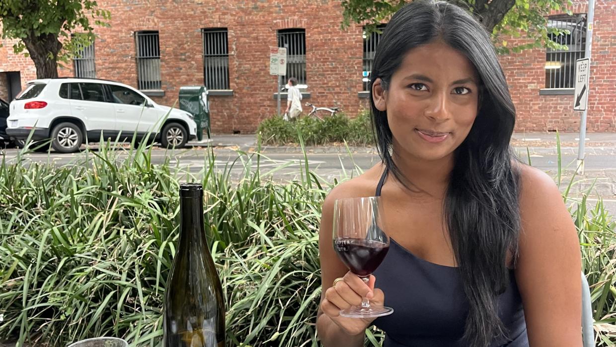 Image of Alisha Jacob sitting at an outside bar with a drink in her hand