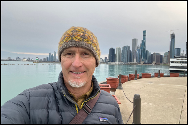 Image of Justin Lewis in front of the Chicago Skyline. He is smiling at the camera.