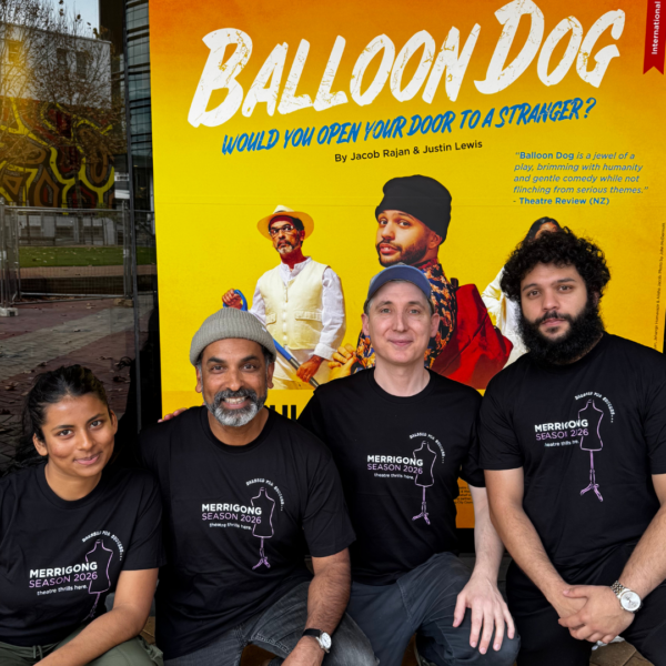 Four people in matching 'Merrigong Season 2026' shirts posing in front of a bright yellow 'Balloon Dog' theatre poster.